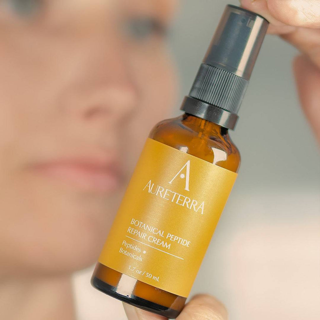 Aureterra Botanical Peptide Cream bottle held in natural light, highlighting the solar-infused botanical formula.